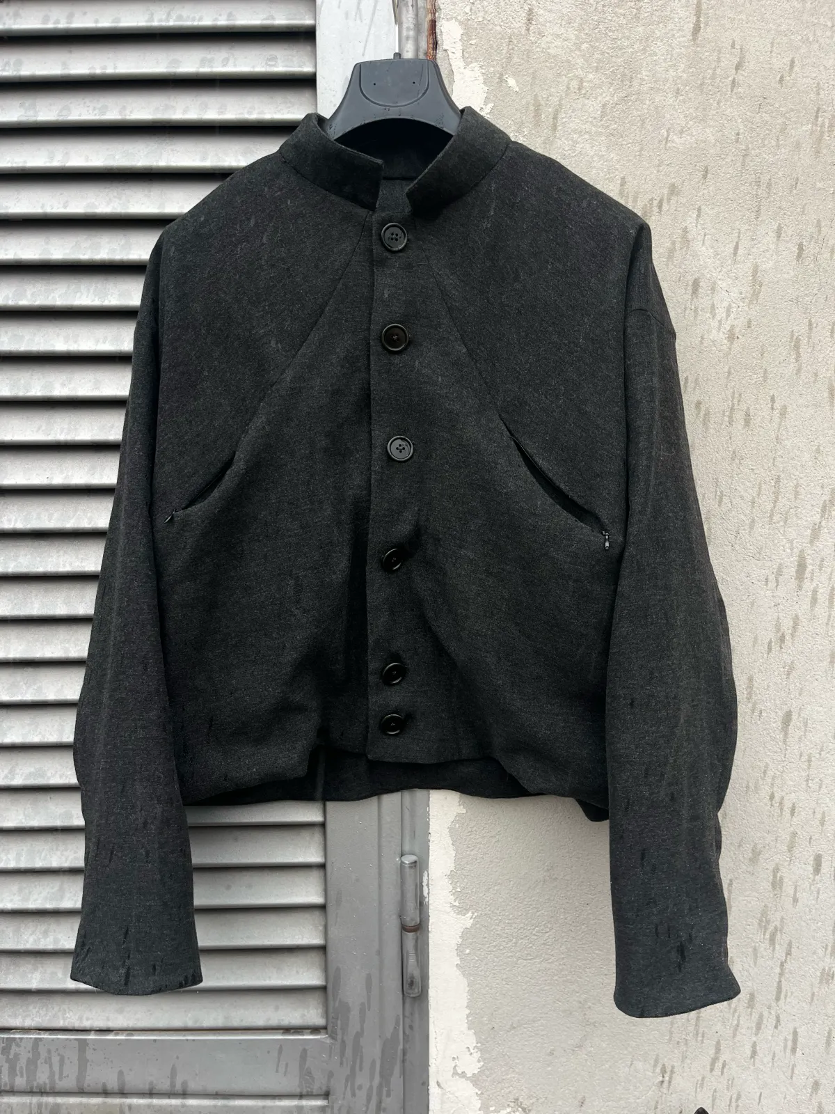 U Jacket di Tommaso Curatella, fronte: giacca in misto lana scura con collo alto, chiusura a 6 bottoni e tasche inserite nella cucitura frontale